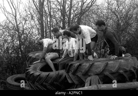 Konkurrenten, die alten Reifen Hindernis Tough Guy Rennen bei Tettenhall, West Midlands, England, UK 1991 Überklettern Stockfoto