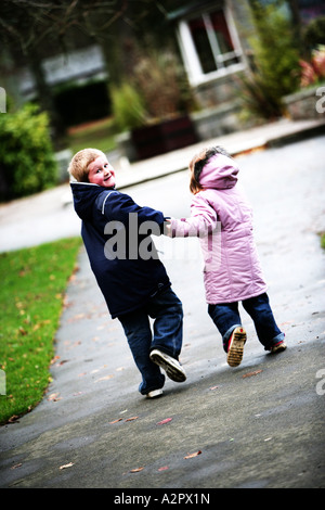 Ein Junge und ein Mädchen liefen einen Park Weg in Richtung der Kamera im Rückblick Stockfoto