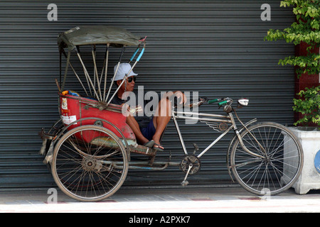 Fahrrad-Rikscha-Fahrer entspannend am Straßenrand, Chiang Mai, Thailand Stockfoto