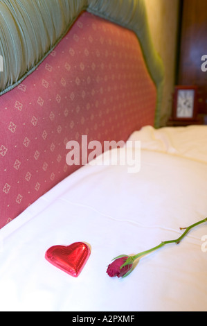 eine rote Rose und Schokolade auf einem Schlafzimmer Kissen im Lake District Hotel Schlafzimmer, Ambleside, Großbritannien Stockfoto