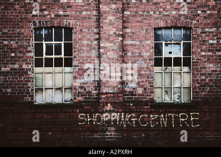 Einem Format Landschaftsbild von einer alten verlassenen Gebäude mit ironischen Graffiti sagen "Einkaufszentrum" unter zertrümmerten Fenstern Stockfoto