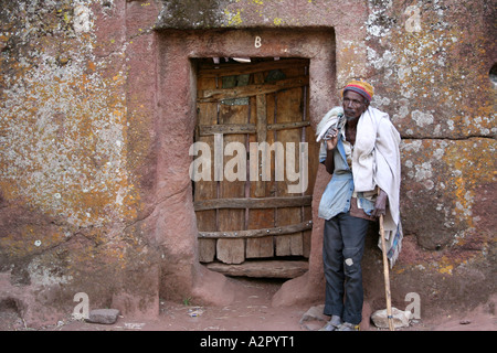 Gatekeeper steht neben der Tür eines Lalibela gehauene Felsenkirchen, Lalibela, Äthiopien Stockfoto