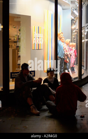 Menschen sitzen auf dem Bürgersteig vor einem Kaufhaus in der Nacht des Arts Festival in Helsinki, Finnland, EU. Stockfoto