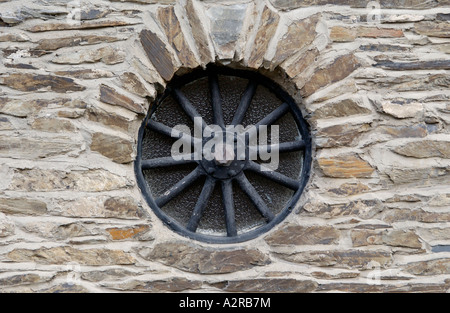 Alten Speichen gusseisernen Rad als rustikale Fensterdetail auf ländlichen Steinhaus in UK Stockfoto