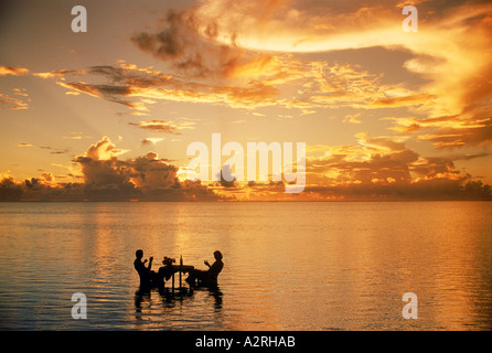 Paar sitzt am Tisch teilen Sonnenuntergang trinken in Lagune inmitten des Pazifischen Ozeans.  Ruhe und Einsamkeit im Urlaubsparadies Stockfoto