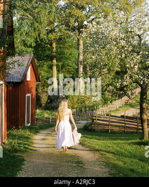 Blonde Frau im weißen Kleid auf Bauernhof in Småland, Schweden Stockfoto