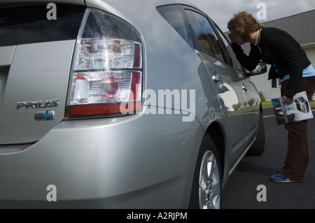 JUNGE FRAU BETRACHTEN 2004 TOYOTA PRIUS-BENZIN-ELEKTRO-HYBRID-AUTO Stockfoto