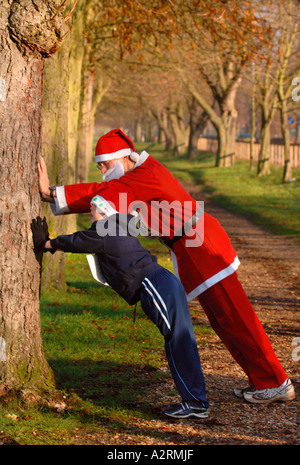 VATER UND SOHN IN VATER WEIHNACHTEN KOSTÜM OUTFITS STRECKE AB VOR EINEM SAISONALEN LAUFEN UK Stockfoto