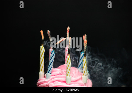 Rauchen-Kerzen auf Geburtstagskuchen schwarzen Hintergrund Stockfoto