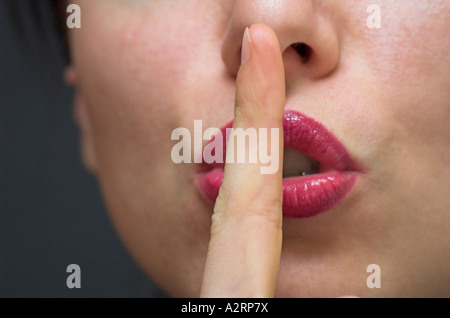 Junge Frau mit Zeigefinger Lippen hautnah Stockfoto