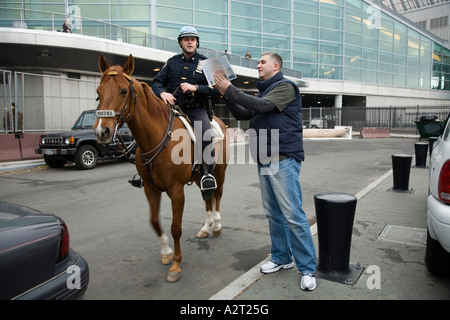 Polizist gibt Anweisungen für Touristen in der Nähe von Government Office South Ferry New York City. USA. Stockfoto