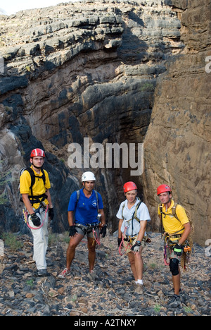 Eine Gruppe von Bergsteigern pause für eine wohlverdiente Verschnaufpause am Rande des Snake Canyon im westlichen Hajar-Gebirge Omans Stockfoto