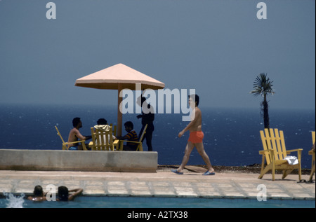 Urlauber stehen herum und Schwimmen im Pool mit dem Blau des Meeres hinter ihnen, Cayo Largo, Kuba Stockfoto