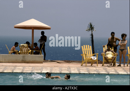 Urlauber stehen herum und Schwimmen im Pool mit dem Blau des Meeres hinter ihnen, Cayo Largo, Kuba Stockfoto