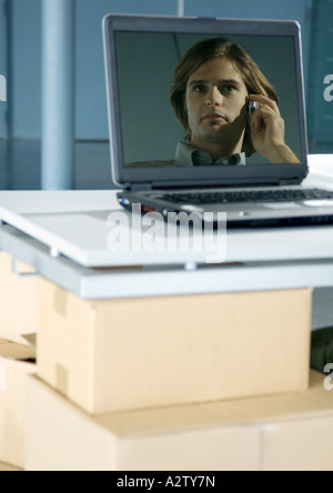 Bild des Mannes mit Handy spiegelt sich in der Laptop-Bildschirm Stockfoto