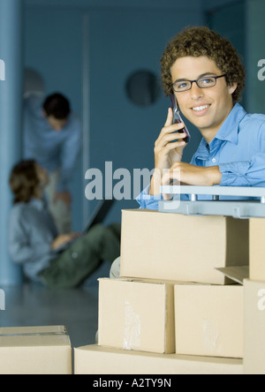 Junger Mann mit Handy, Karton, Boxen im Vordergrund Stockfoto