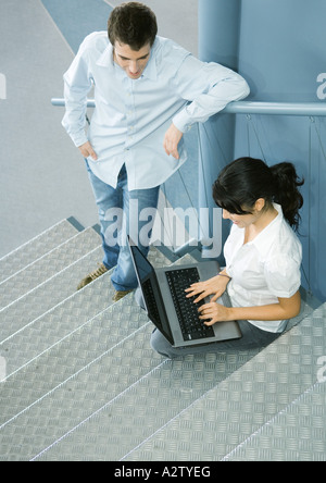 Zwei Kollegen sprechen, man sitzt auf der Treppe mit laptop Stockfoto