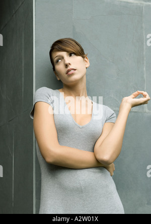 Junge Frau Wand gelehnt, Arm über Körper, wegschauen Stockfoto