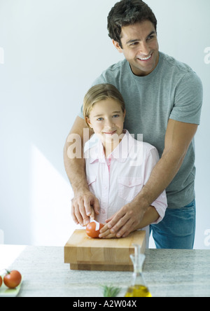 Mann hilft Tochter geschnittene Tomaten Stockfoto