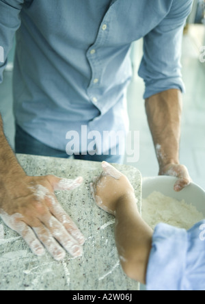 Mädchen und Vater wischte Mehl auf Zähler in die Rührschüssel geben, verkürzte Ansicht Stockfoto