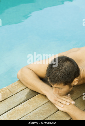 Mann, der vom Rand der Swimmingpool liegt Stockfoto