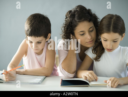 Junge Frau, die Kinder bei den Hausaufgaben zu helfen Stockfoto