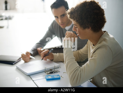 Vater Sohn im Teenageralter bei Hausaufgaben helfen Stockfoto