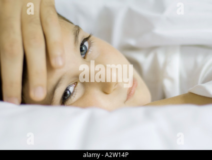 Kind im Bett mit Vaters Hand auf Stirn Stockfoto