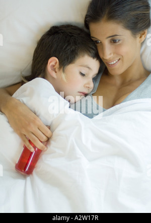 Kind hinlegen mit Kopf auf Mutters Schulter, Mutter Holding Flasche Medizin Stockfoto