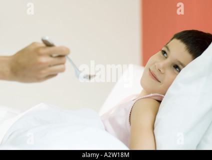 Kind im Bett, gefüttert mit Löffel Stockfoto