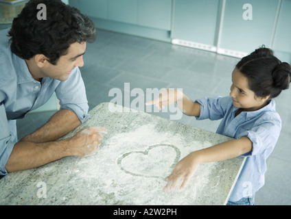 Vater und Tochter kochen zusammen, Herz in Mehl auf Theke gezogen Stockfoto