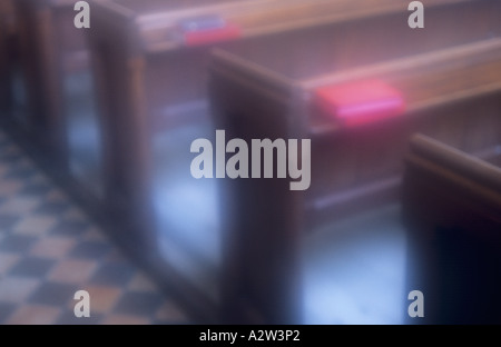 Atmosphärische einfachen hölzernen Kirchenbänken mit roten und blauen Bücher auf Gesimsen und einer karierten schwarz und Orange Fliesenboden Stockfoto