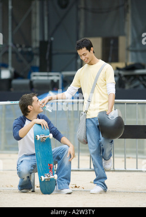 Teen Männchen, mit Skateboard die anderen Holding-Helm Stockfoto
