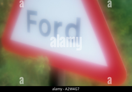 Impressionistische roten und weißen dreieckigen Roadsign auf eine Stelle im Rasen Warnung vor einer Furt Stockfoto