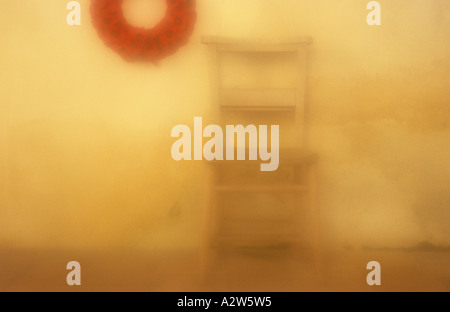 Atmosphärische einsame Holz Stuhl warten neben Gedenktag Kranz von Mohnblumen auf Kirchenmauer in gold Licht getaucht Stockfoto