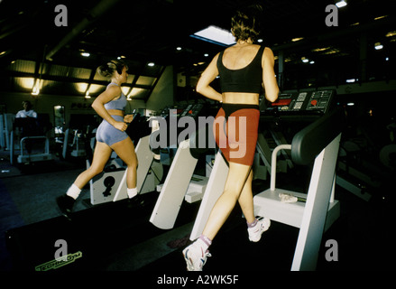 eine Frau in schwarz Sport Top und Tanga läuft auf einem Laufband eine andere Frau benutzt das Laufband neben ihr in einem Buckinghamshir Stockfoto