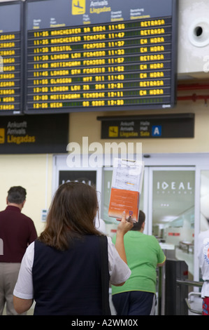 spanische weibliche Tourguide wartet vor Ankunft Message Board mit Liste der Passagiere am Flughafen Süd Reina Sofia Sur TFS Stockfoto