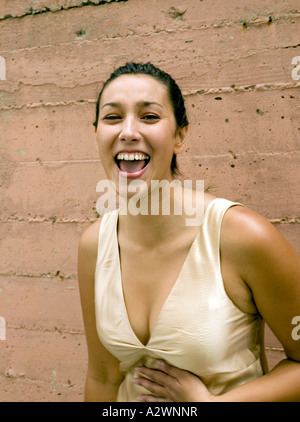 Junge Frau von Mauer stehend, lachend, Porträt Stockfoto