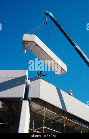 Bauindustrie. Arbeiter am Hochhaus Regie Kranführer Positionierung große konkrete Abschnitt. Stockfoto