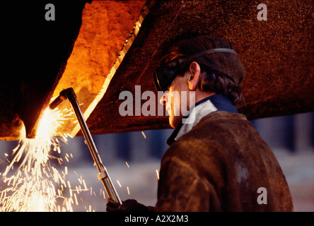 Vereinigtes Königreich. Nahaufnahme Seitenansicht eines Mannes im Schiffbau Werft Schweißen mit Autogen Fackel. Stockfoto
