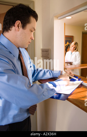 Patient anmelden bei der Ankunft in der Arztpraxis. Im Mietvertrag zu unterzeichnen. Stockfoto