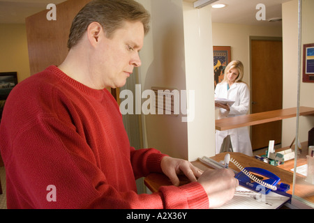 Patient anmelden an der Rezeption vor seinem Arzt zu sehen. Stockfoto