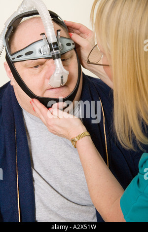 Krankenschwester stellt ein CPAP-Gerät Continuous Positive Airway Pressure auf Patienten mit Schlaf-Apnoe. Er weist ihn, wie es verwendet wird. Stockfoto