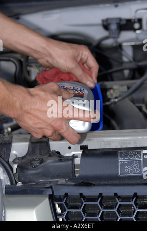 Einen männlichen Fahrzeug-Techniker füllt sich ein Motor mit Öl in einer schnellen Service Garage Stockfoto