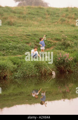 Kinder. Zwei Jungs im Freien am Ufer Fischen mit Netzen. Stockfoto