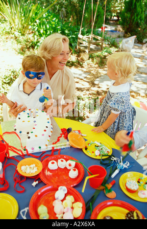 Kinder Teeparty im Freien im Garten mit Großmutter. Stockfoto
