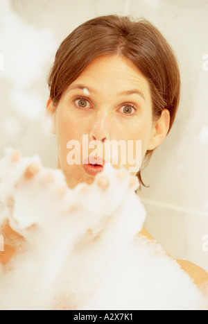 Indoor-Porträt der jungen Frau im Bad Seifenblasen in die Kamera. Stockfoto