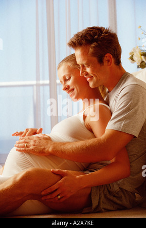Junges Paar sitzen im Innenbereich. Ein Baby erwartet. Stockfoto