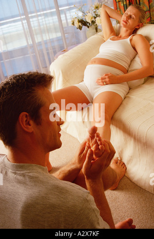 Familie. Schwangerschaft. Paar drinnen. Mann, Fußmassage, schwangere Frau zu geben. Stockfoto
