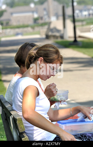 Zwei weibliche Büroangestellte sitzen im Park zu Mittag. Stockfoto